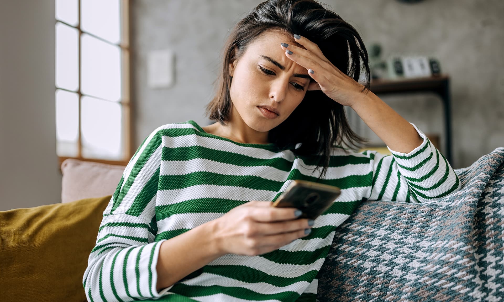 Woman sitting on couch with head in hand