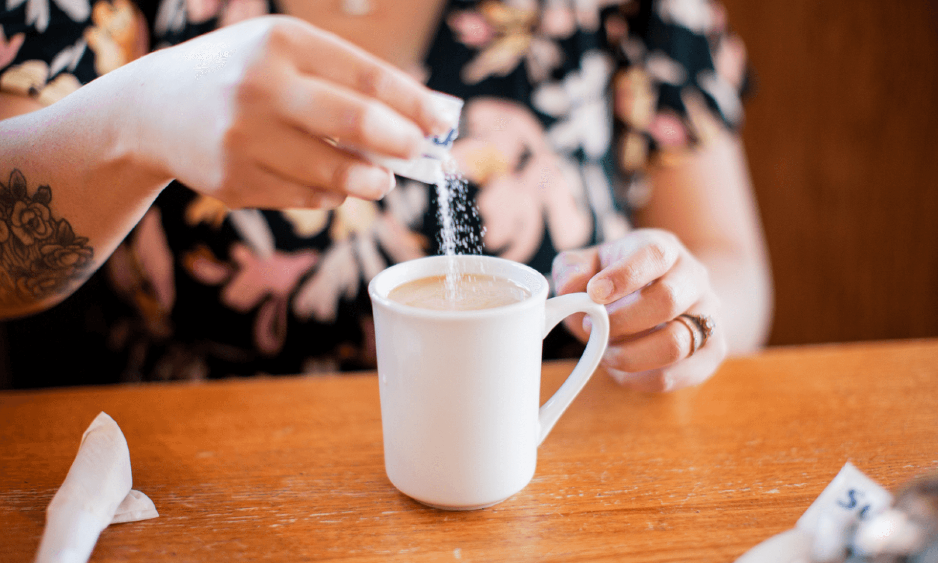 A person putting sugar in their coffee